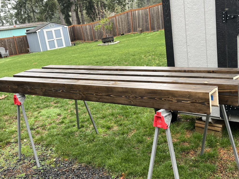 Fence boards being stained on sawhorses — preparation work